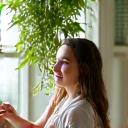 A young woman smiling as she waters a hanging plant.